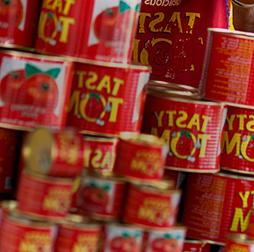 A stack of Tasty Tom tins full of tomato paste, Olam also manufactures pasta, biscuits, yoghurt drinks and edible oils for African markets.